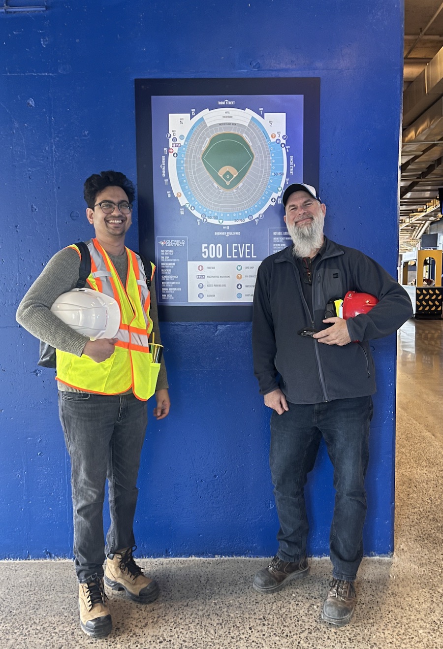 Eric Costa on site at Rogers Centre during the under-seat DOT build, beside a 500-level seating map